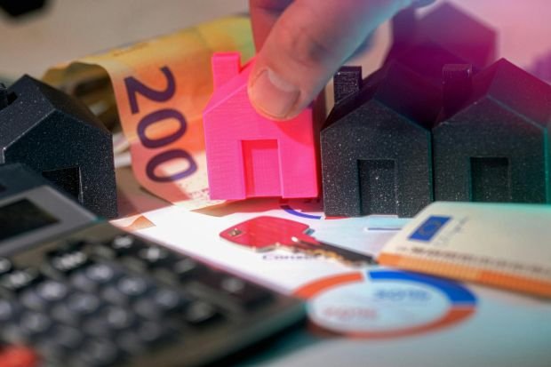 Miniature houses, Euro bills, and calculator representing real estate investment.