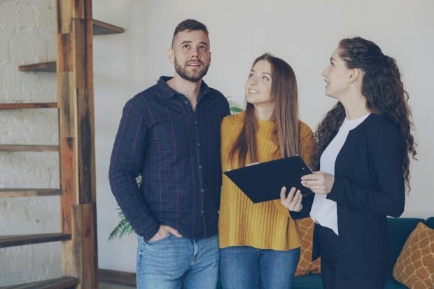 Young couple exploring a new home with their real estate agent, discussing options and features.