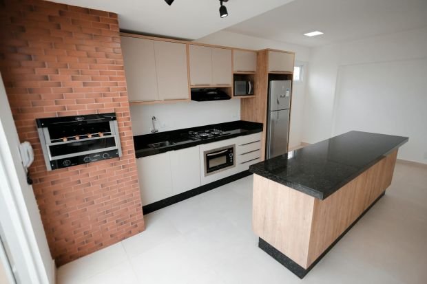 Contemporary kitchen interior featuring a brick wall, sleek countertops, and a central island.