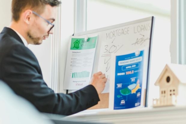 Real estate agent analyzing mortgage loan details on a whiteboard in an office setting.