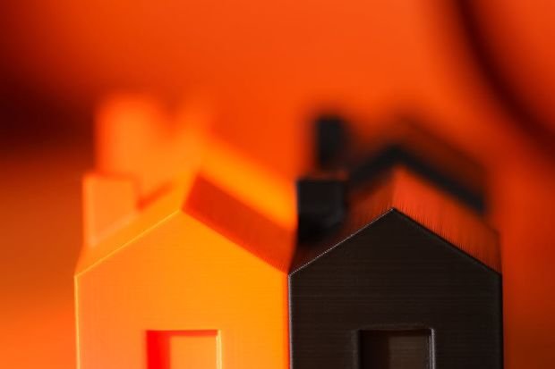 Vibrant and contrasting orange and black miniature house models symbolizing real estate concepts.