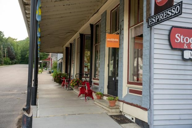 Inviting café facade with red chairs and flowers on a quaint small-town street.
