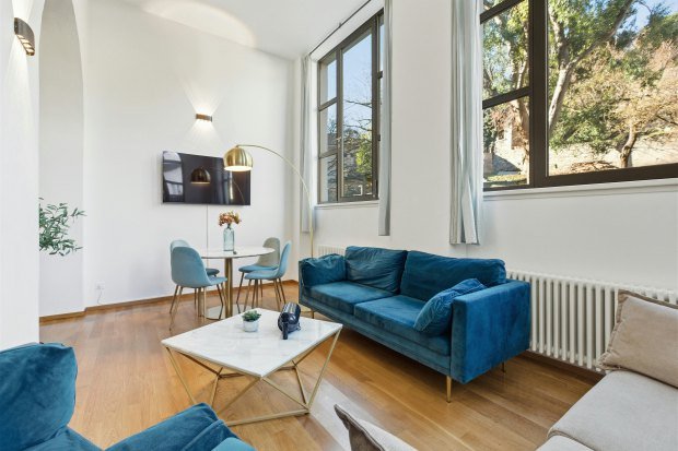 Bright and stylish living room with blue velvet sofa, large windows, and minimalist decor.